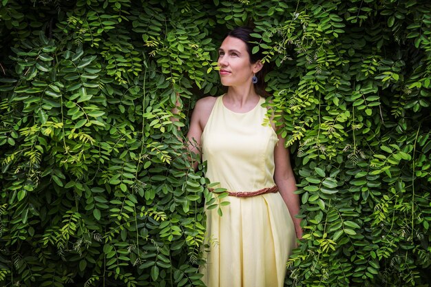 나뭇잎을 만지는 무성한 녹색 식물에 둘러싸여 머물고 있는 여성