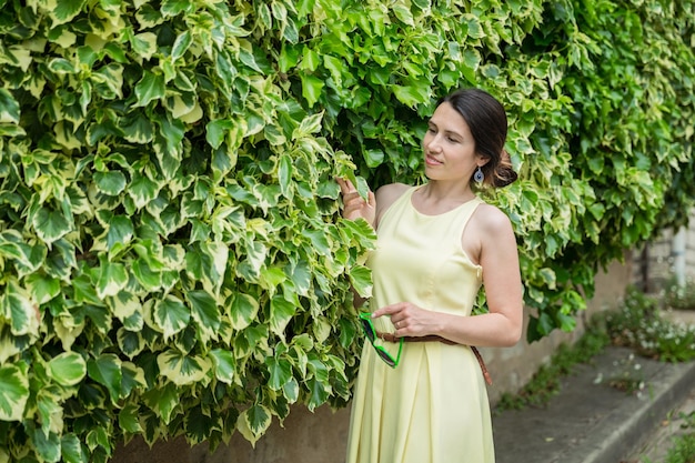 Woman staying surrounded by lush green plants touching leaves