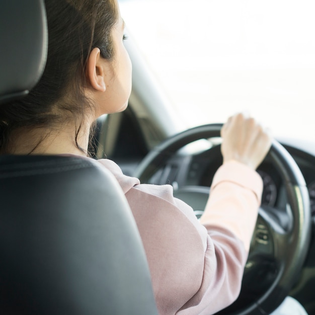 Woman at steering wheel over the shoulder view