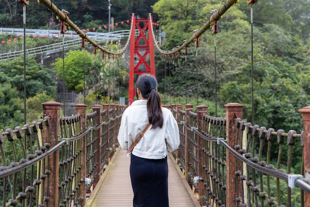 Photo woman stepping onto the suspension bridge in wulai of taiwan