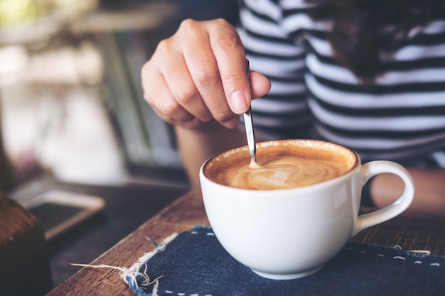 女性、スプーンでコーヒーをかき混ぜる