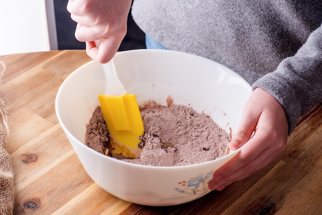 A woman stirring muffin dough with other ingredients in a bowl