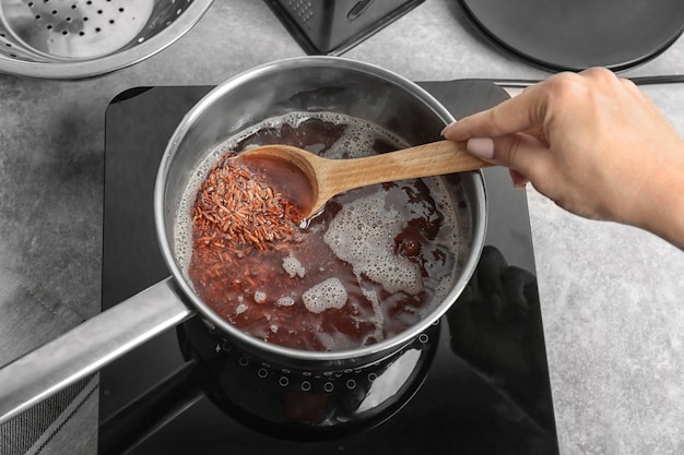 Woman stirring rice in saucepan