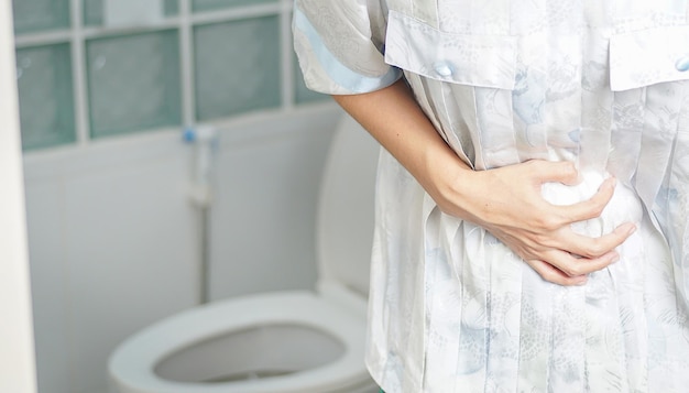 The woman stood in the bathroom in the toilet With severe diarrhea Use both hands to hold