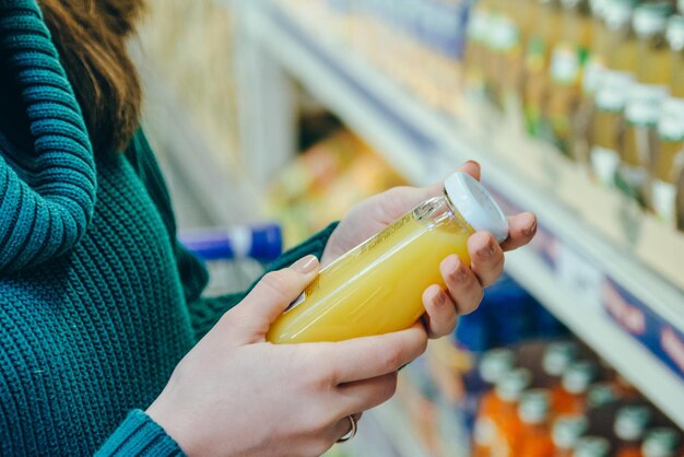 Woman in store read ingredients of juice grocery shopping copy space