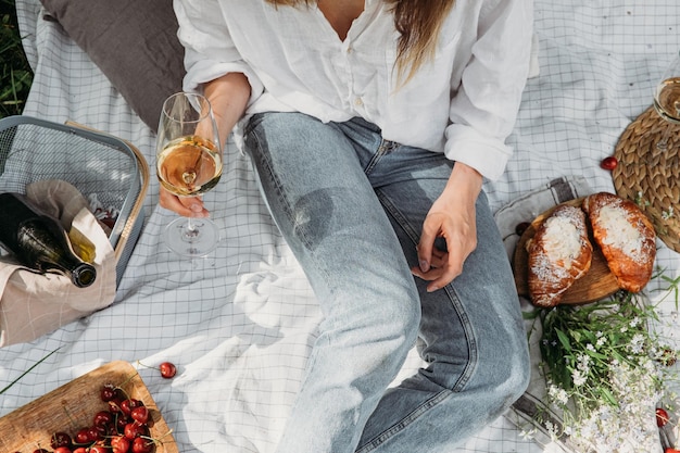 Woman in straw hat on picnic holding a glass of wine top view aesthetic picnic outdoors with wine