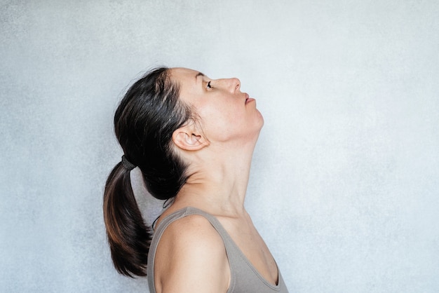 A woman stretches her neck using the McKenzie method is a form of physical therapy, neck pain relief exercises