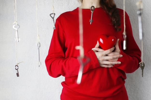 Woman stretches out his hand with a shape of red heart surrounded with a key threads