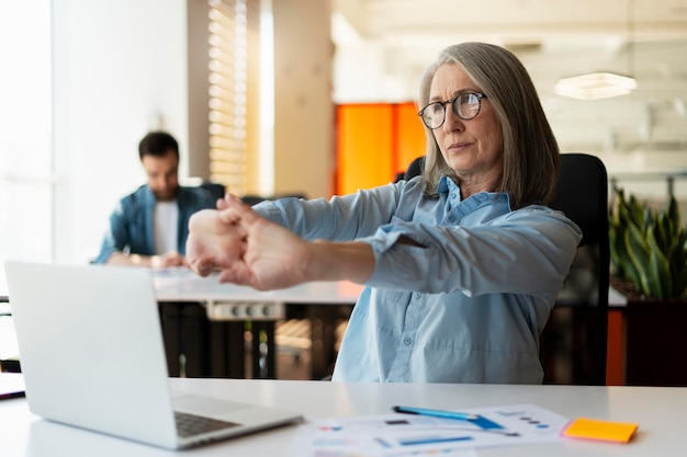 Photo woman stretching arms after long time sitting at laptop working in office