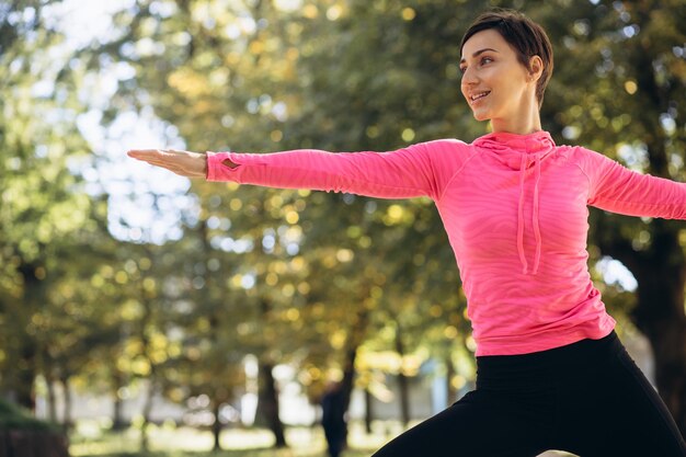 Foto donna che si estende nel parco autunnale al mattino