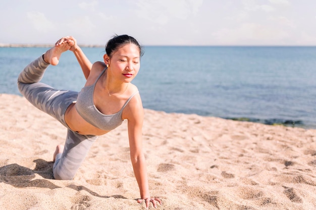 Photo woman stretching on the beach with yoga poses