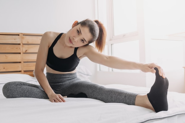 Photo woman stretching and cool down after workout in her apartment room