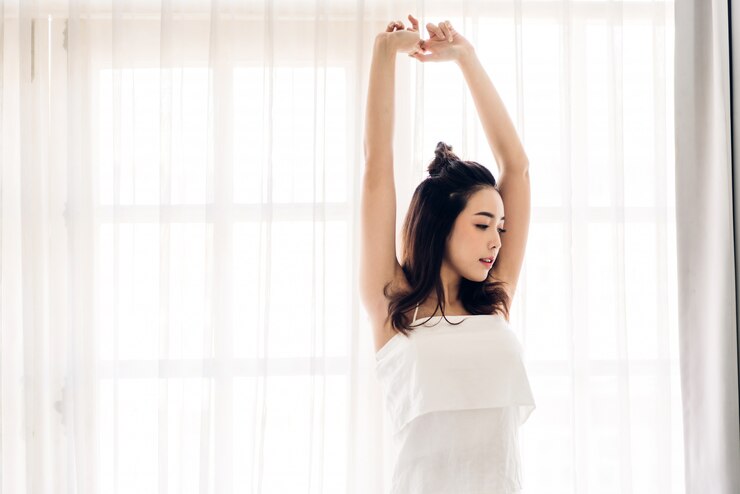 自宅で朝目を覚ました後幸せとリラックスしたストレッチの女性