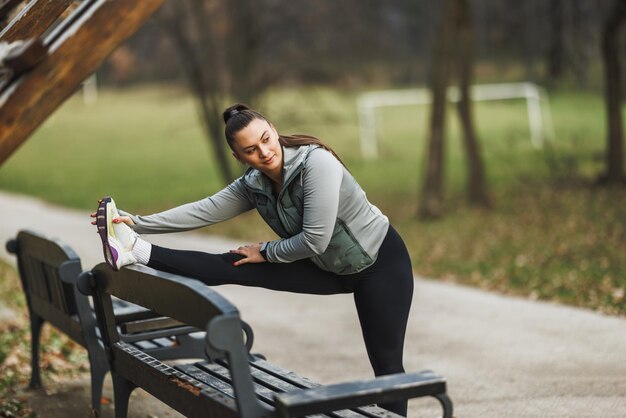 Foto donna che si allunga le gambe su una panchina del parco