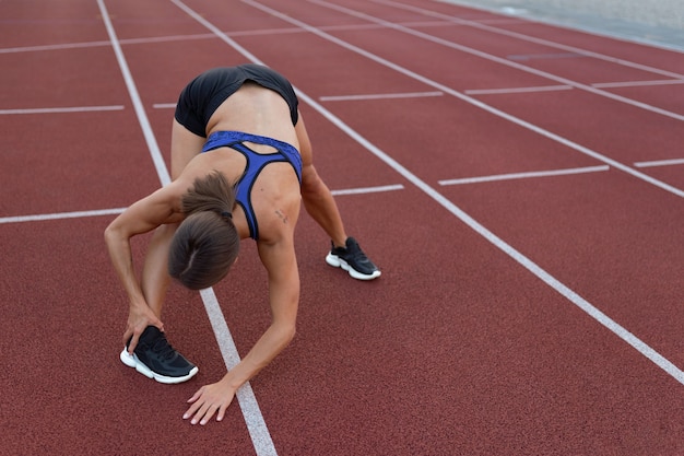 Photo woman stretching on running track high angle