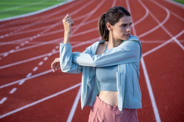 Foto una donna che si allunga su una pista con una maglietta blu.