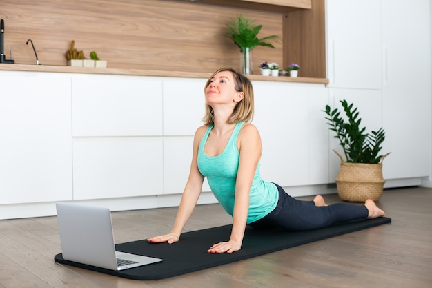 Woman stretching while doing yoga online at home