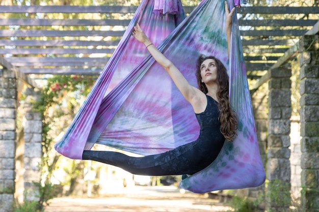 Photo a woman stretching in yoga hammock and looking up