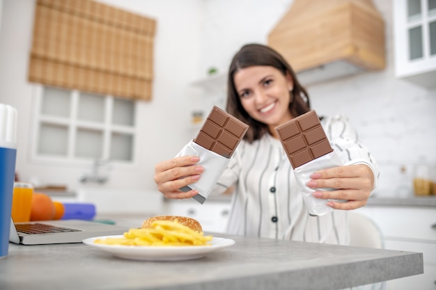 Woman in a striped blouse holding two bars of chocolate