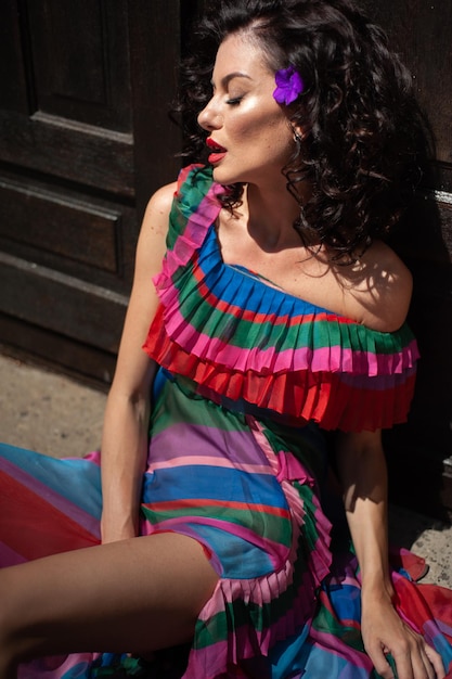 A woman in a striped dress is sitting on the ground.