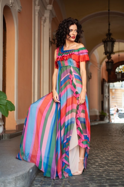 A woman in a striped dress stands in a courtyard.