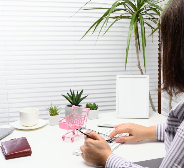 Woman in a striped shirt sits at a table and works at a computer. Remote work, freelance. Online shopping