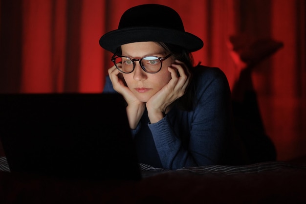 Woman in a striped sweatshirt and hat eats popcorn and watches a movie on tv or a tv series at