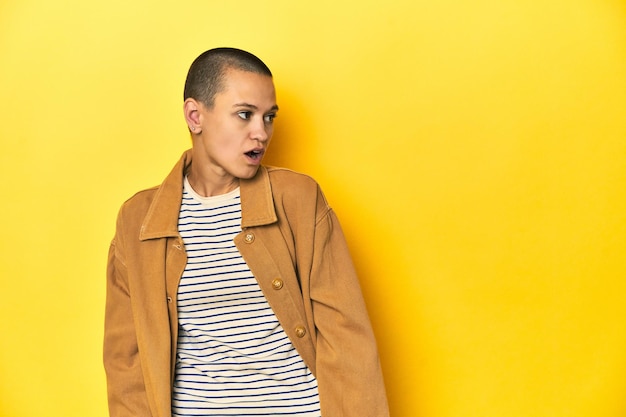 Photo woman in striped tee and denim shirt yellow backdrop being shocked because of something she has seen