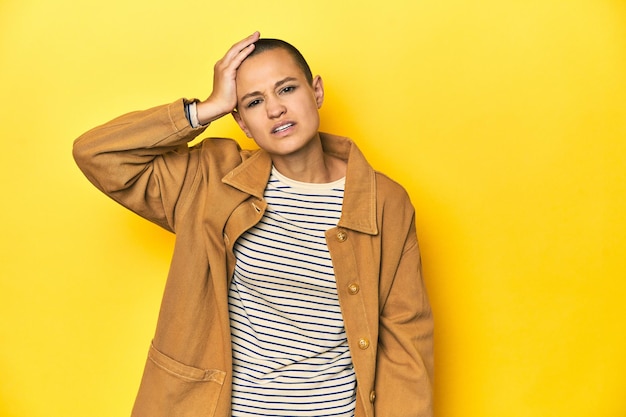 Woman in striped tee and denim shirt yellow backdrop being shocked