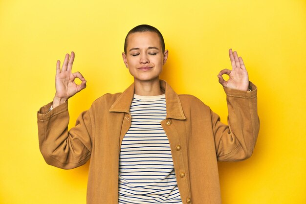 Photo woman in striped tee and denim shirt yellow backdrop relaxes after hard working day