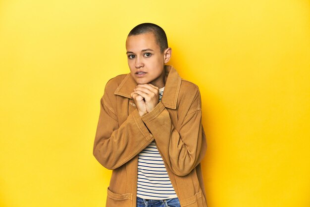 Photo woman in striped tee and denim shirt yellow backdrop scared and afraid