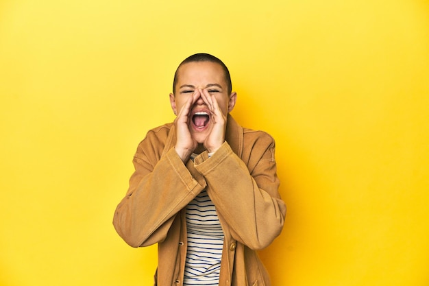 Woman in striped tee and denim shirt yellow backdrop shouting excited to front