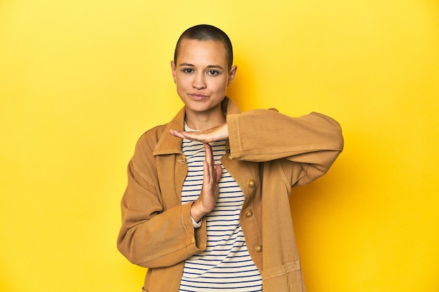 Photo woman in striped tee and denim shirt yellow backdrop showing a timeout gesture