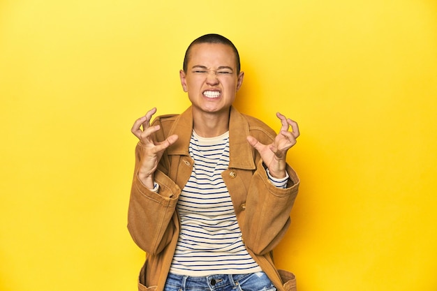 Photo woman in striped tee and denim shirt yellow backdrop upset screaming with tense hands