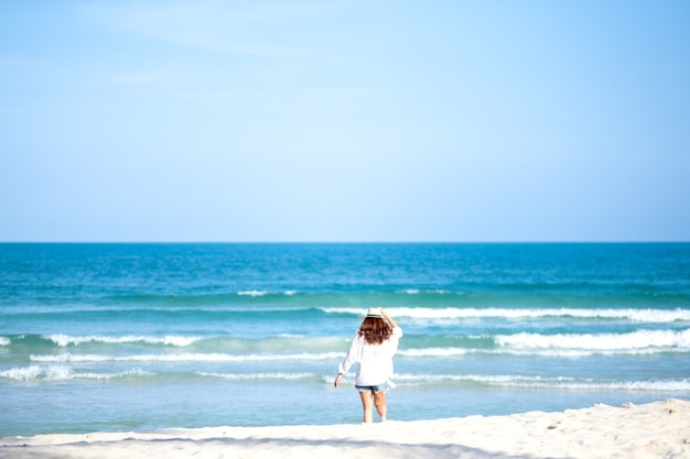 海と青空を背景にビーチを散歩する女性