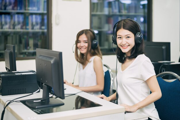 女子学生がITルームで勉強しながらコンピューターでポーズします。