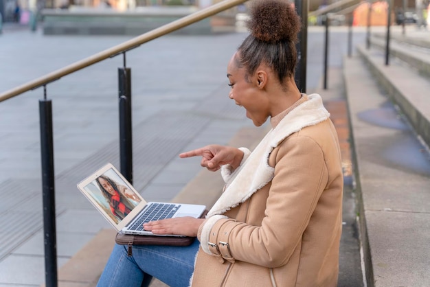 woman student study working on stairs in the city   watching online education webinar using a laptop