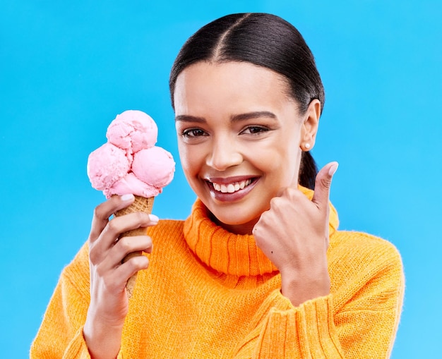 Женский студийный портрет и мороженое с поднятыми большими пальцами, улыбка и счастье на синем фоне