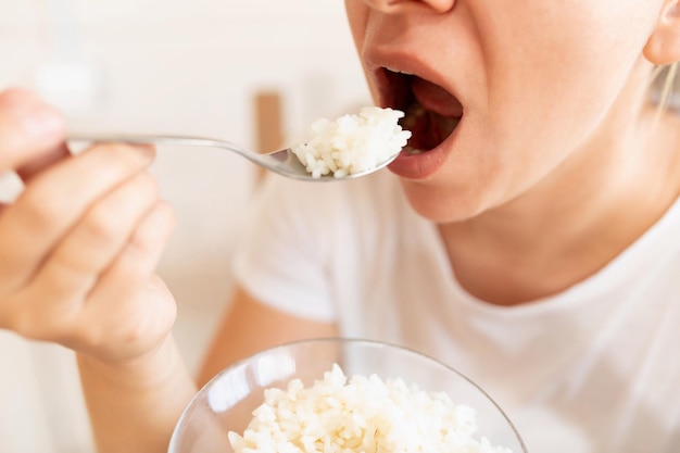 A woman stuffs a spoonful of rice into her mouth concept of proper nutrition