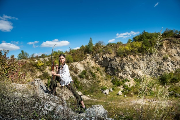 Woman in style native American Indian holding bow and arrow in nature