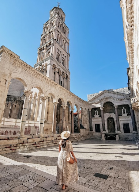 Woman in stylish summer dress standing in Peristyle of Diocletian's palace in Split, Croatia.
