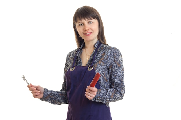 Woman stylist in an apron with tools in hands smiling on camera isolated on white background