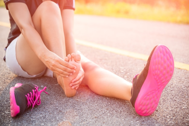 Photo woman suffering from an ankle injury while exercising and running.