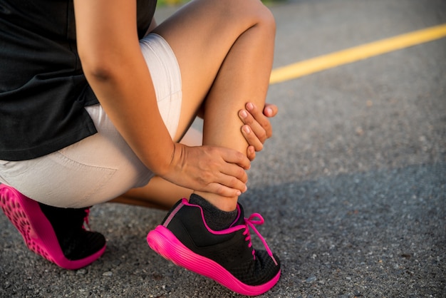 Woman suffering from an ankle injury while exercising and running.