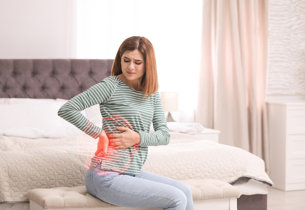 Woman suffering from back pain after sleeping on uncomfortable mattress at home