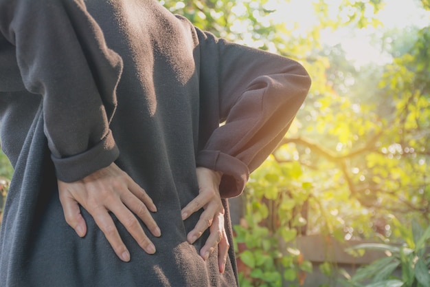 屋外での腰痛、脊髄損傷および筋肉の問題に苦しむ女性。