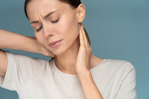 Photo woman suffering from chronic neck pain, gently massages with hands, feeling tired