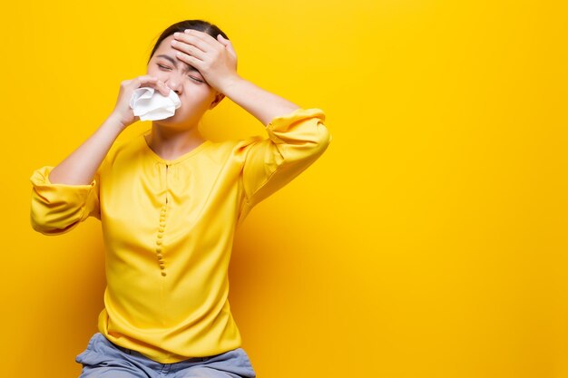 Woman suffering from cold against yellow background