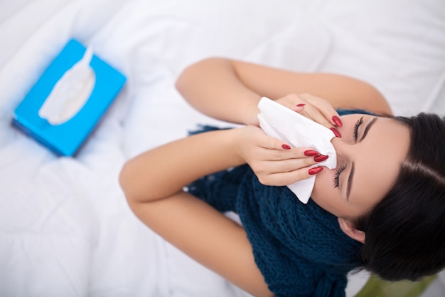 Woman Suffering From Cold Lying In Bed With Tissue