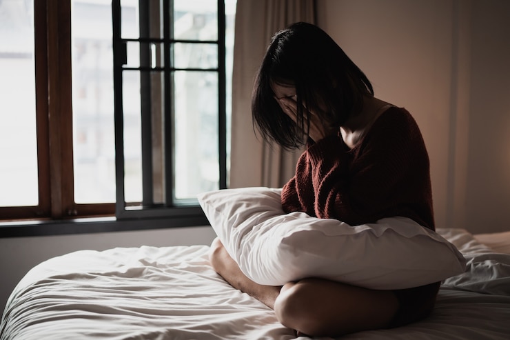 Photo 寝室のベッドに座ってうつ病に苦しんでいる女性